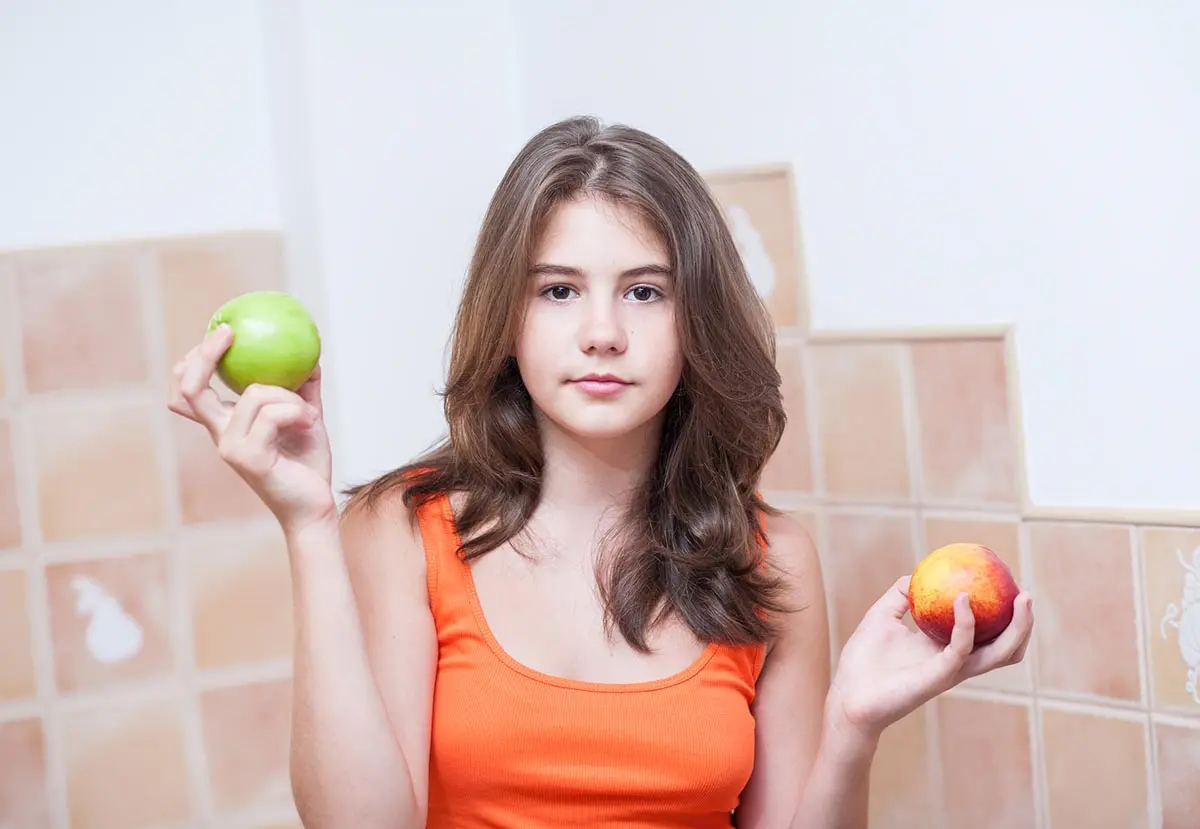 Девочка показала персик. Девочка держащая персик в руке. Девушка с зеленым яблоком в руке. Персик девочки подростка. Девушка в оранжевой майке с фруктами.